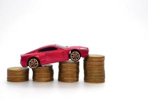 kleines rotes Automodell auf einer großen Menge gestapelter Münzen. Wirtschaft und Geschäftskonzept. foto