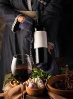 eine vertikale Aufnahme einer Person in traditioneller Tracht, die eine Weinflasche zeigt foto