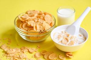 cornflakes schüssel frühstück und snack für ein gesundes lebensmittelkonzept, morgendliches frühstück frisches vollkornmüsli, cornflakes mit milch auf gelbem hintergrund foto