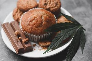 Cannabis-Lebensmittelkekse mit Kuchenschokoladen-Cannabisblatt-Marihuana-Kraut auf Holz- und dunklem Hintergrund, köstlicher süßer Dessert-Keks mit Hanfblattpflanze thc cbd-Kräuter-Nahrungsmittelsnack und Medizin foto