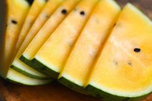 süße Wassermelonenscheiben Stücke frische Wassermelone tropische Sommerfrucht, gelbe Wassermelonenscheibe auf Holzhintergrund foto