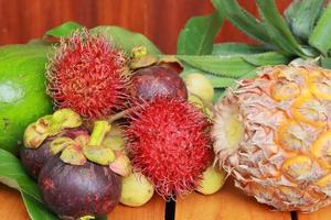 Viele reife Früchte mit reifer Ananas auf Holzhintergrund foto