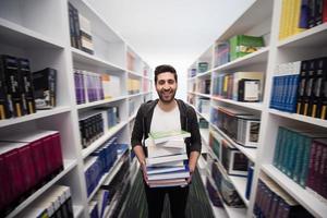 schüler, der viele bücher in der schulbibliothek hält foto