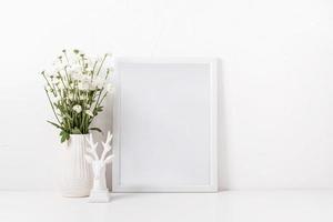 weißes rahmenmodell mit chrysanthemenblumen in einer vase auf einem weißen tisch foto