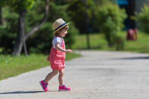 kleines Mädchen, das im Sommerpark läuft foto