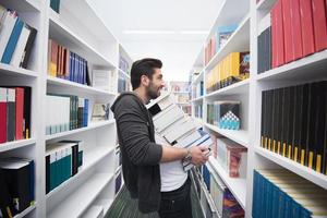 schüler, der viele bücher in der schulbibliothek hält foto