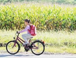 Schulmädchen, das mit dem Fahrrad zur Schule fährt foto