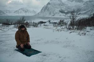 muslimischer reisender, der an einem kalten, verschneiten wintertag betet foto