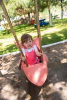 kleines Mädchen, das auf einem Spielplatz schwingt foto