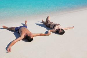 glückliches junges Paar, das den Sommer am Strand genießt foto