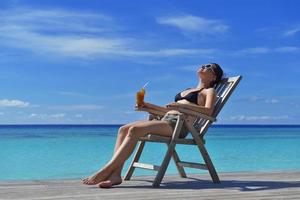 schöne junge frau mit einem getränk am meer foto