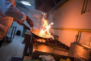 Koch macht Flamme auf Essen foto