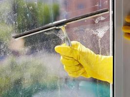 hand im gelben handschuh reinigt fenster mit rakel foto