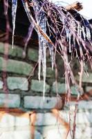 Eiszapfen und Zweige auf dem Dach des Hauses foto