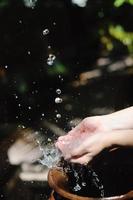 frisches Wasser auf die Hände der Frau spritzen foto