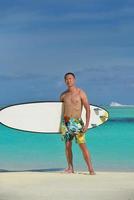 Mann mit Surfbrett am Strand foto