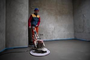 arbeiter, der sand- und zementestrichboden durchführt und poliert foto