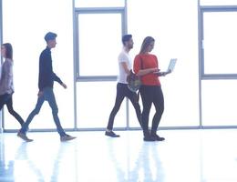 studentin steht mit laptop, personengruppe vorbei foto