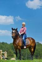 glückliche Frau reitet Pferd foto