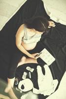 Draufsicht einer schwangeren Frau, die die Liste der Babykleidung überprüft foto