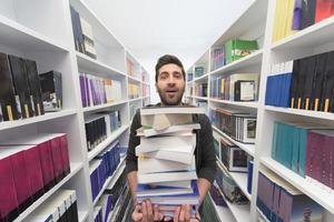 schüler, der viele bücher in der schulbibliothek hält foto