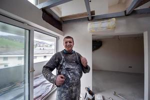 Porträt eines Bauarbeiters mit schmutziger Uniform in der Wohnung foto