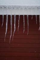 Eiszapfen auf dem Dach eines roten Hauses in Norwegen foto