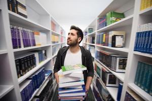 schüler, der viele bücher in der schulbibliothek hält foto