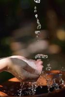 frisches Wasser auf die Hände der Frau spritzen foto