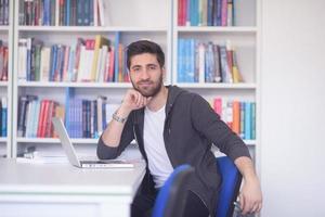 Schüler in der Schulbibliothek mit Laptop für die Recherche foto