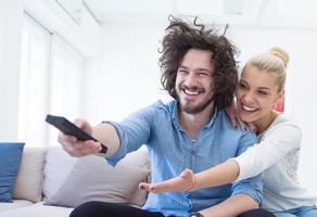 junges Paar auf dem Sofa vor dem Fernseher foto