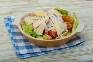 Caesar-Salat mit Hähnchen in einer Schüssel auf Holzhintergrund foto