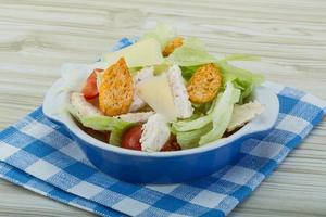 Caesar-Salat mit Hähnchen in einer Schüssel auf Holzhintergrund foto