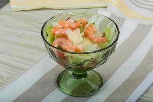 Caesar-Salat mit Garnelen in einer Schüssel auf Holzhintergrund foto