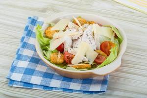 Caesar-Salat mit Hähnchen in einer Schüssel auf Holzhintergrund foto