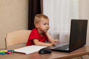 Online-Fernunterricht. Das Kind schaut aufmerksam auf den Laptop und studiert die Zeichenstunde online im Internet. Online-Schule. foto