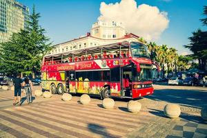 batumi, georgia, 2022 - touristischer spaziergang auf der straße mit dem roten zweistöckigen doppeldecker-klassischen besichtigungsbus durch die stadt. berühmte Attraktion der Stadt foto