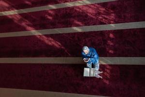 muslimischer mann, der allah allein in der moschee betet und islamisches heiliges buch liest foto