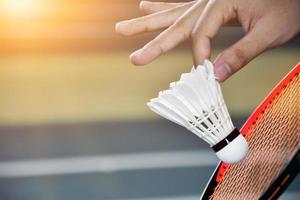 Badmintonspieler hält Schläger und Federball mit weißer Creme vor das Netz, bevor er ihn auf einer anderen Seite des Platzes serviert. foto