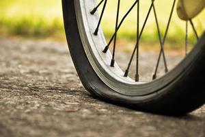 Nahaufnahme des Fahrrads, das einen platten Reifen hat und auf dem Bürgersteig geparkt ist, unscharfer Hintergrund. weicher und selektiver Fokus auf Reifen. foto