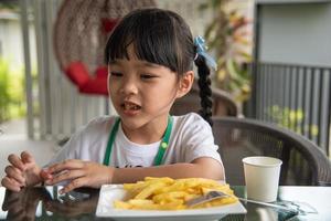 Junges asiatisches Mädchen, das Pommes frites isst, junges Kind, Spaß, glücklich, Kartoffel-Fast-Food. foto