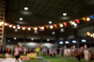 Verschwommenes Bild von Nachtmarktfestival-Leuten, die auf der Straße mit hellem Bokeh für den Hintergrund gehen. foto