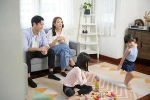 asiatische familie mit kindern, die spielen und turm aus bunten holzspielzeugblöcken im wohnzimmer zu hause bauen, lernspiel. foto
