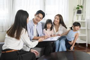 asiatisches familientreffen mit weiblichen immobilienmaklern oder versicherungsberatern, die förderungen, hypotheken, darlehen, eigentum und medizinisches krankenversicherungskonzept anbieten. foto