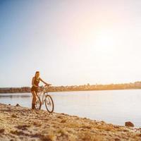 Frau auf einem Fahrrad in der Nähe des Wassers foto