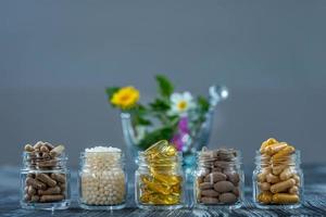 Flasche Pillen Nahrungsergänzungsmittel gesunde Medizin, Medikamente Gesundheitsbehandlung Zusatzstoffe Apotheke mit weißem Keramikmörser mit frischen Heilpflanzen im Hintergrund foto