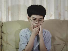 Der kleine asiatische Junge leidet unter Zahnschmerzen. er ist traurig mit zahnschmerzen, zahnkrankheiten, kindern, die an zahnproblemen leiden. Termin Zahnarzt planen. foto