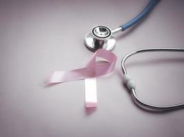brustkrebsbewusstsein rosa band mit arztstethoskop auf rosa hintergrund, oktobersymbol, gesundheits- und medizinkonzept foto