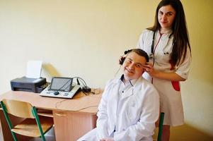 Attraktive Ärztin im weißen Kittel, die die Gesundheit ihrer Patientin untersucht. foto