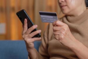 nahaufnahme hand mit kreditkarte bezahlen kontaktlos online beim mobilen app-shopping foto